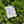 Small card with 'Give Yourself Time' text on a floral pattern, placed on green foliage.